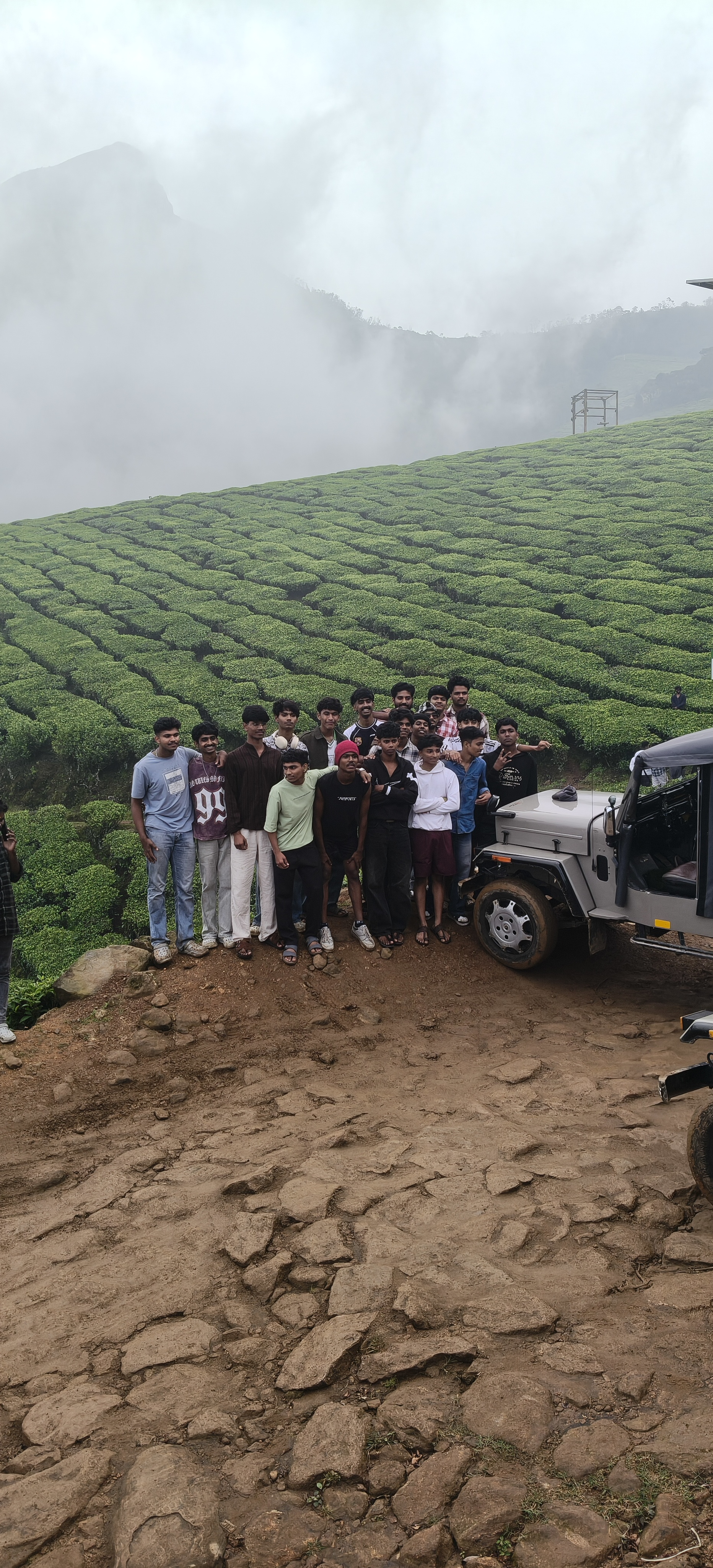 Kolukkumalai Sunrise Point jeep safari stop with tea plantation hills and waterfall backdrop